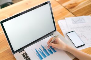 Przedsiębiorca analizujący wykresy finansowe na laptopie w celu optymalizacji kosztów w firmie